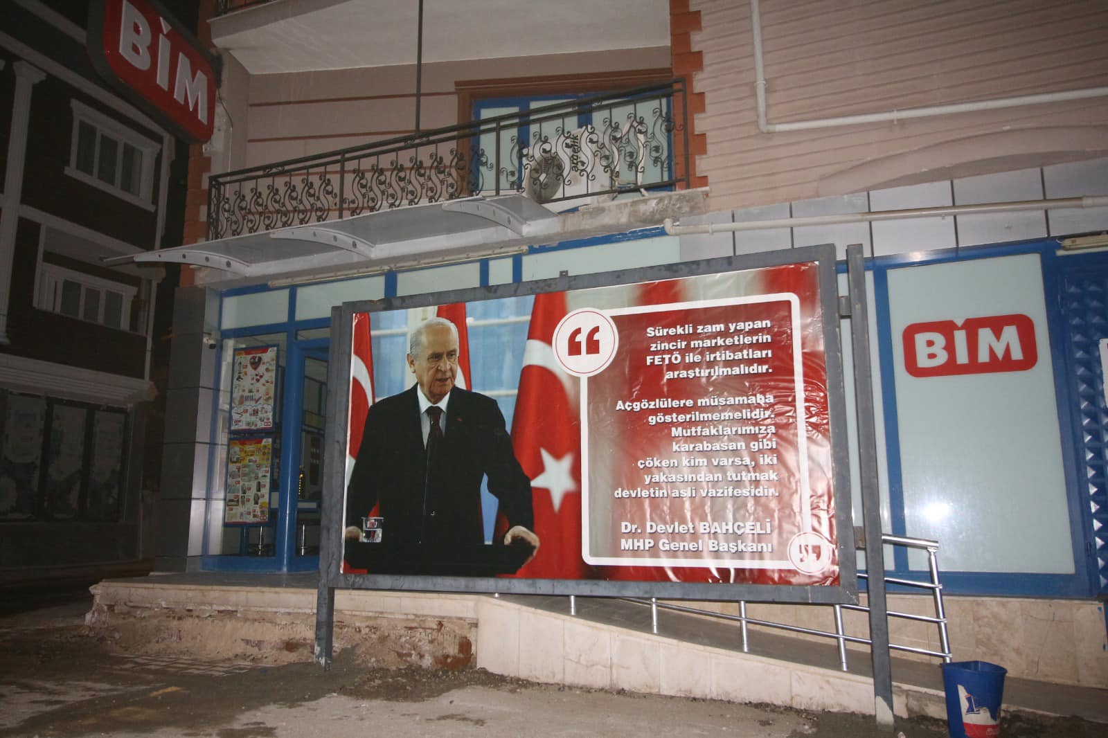 MHP’Lİ TEFENNİ BELEDİYESİ, İLÇEDEKİ ZİNCİR MARKET ŞUBESİNİN ÖNÜNE, ÜZERİNDE DEVLET BAHÇELİ’NİN SÖZLERİNE YER VERİLEN REKLAM PANOSU YERLEŞTİRDİ