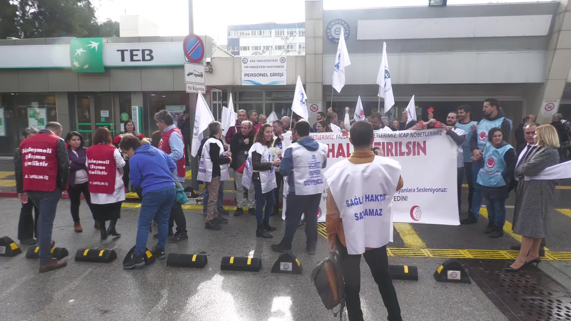 EGE ÜNİVERSİTESİ HASTANESİ ÇALIŞANI SAĞLIKÇILARDAN HASTANE YÖNETİMİNE KIRMIZI KARTLI PROTESTO: “HAK GASBINI ALIŞKANLIK HALİNE GETİRMENİZE İZİN VERMEYECEĞİZ"